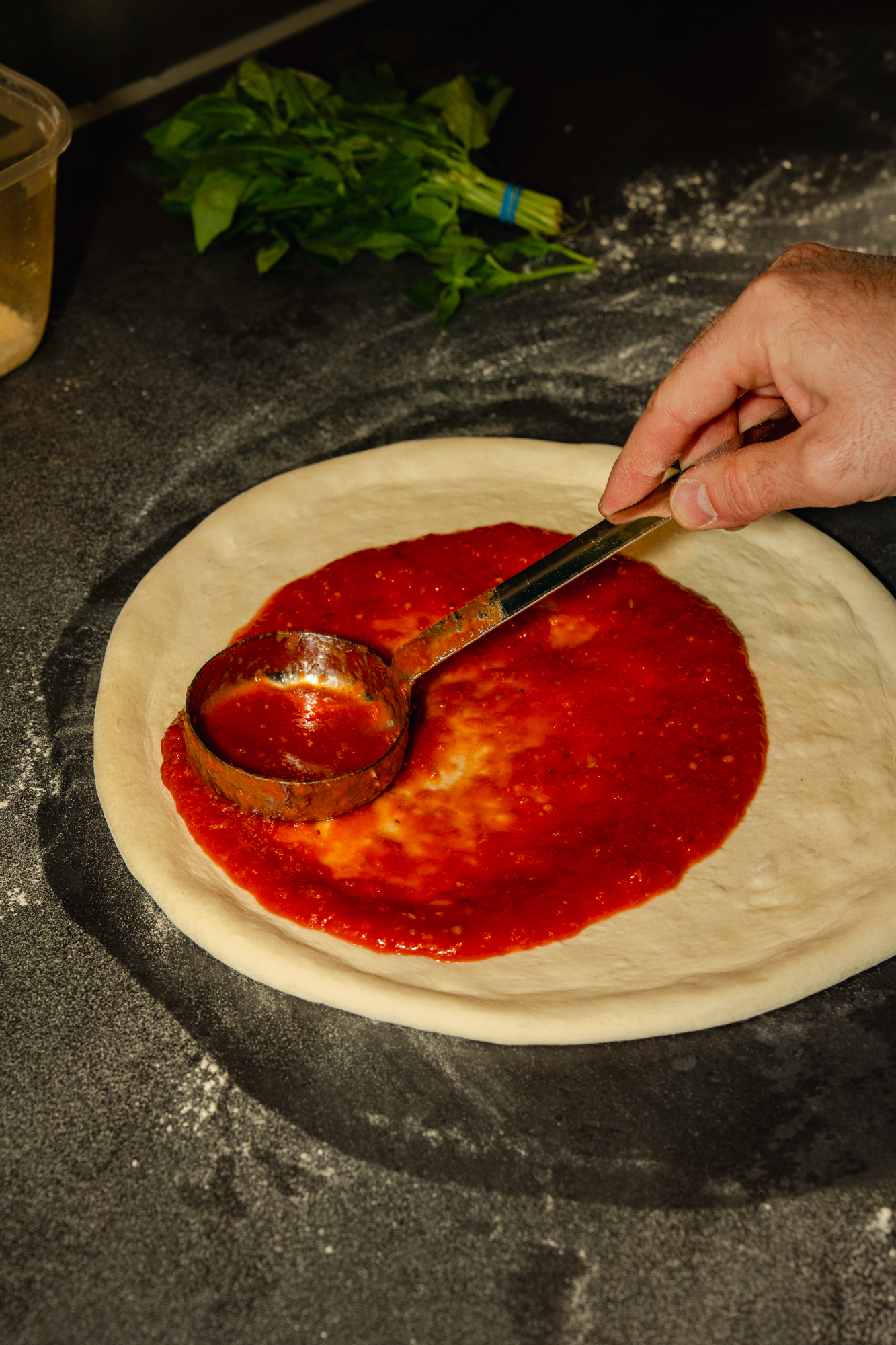 Spreading tomato sauce on dough